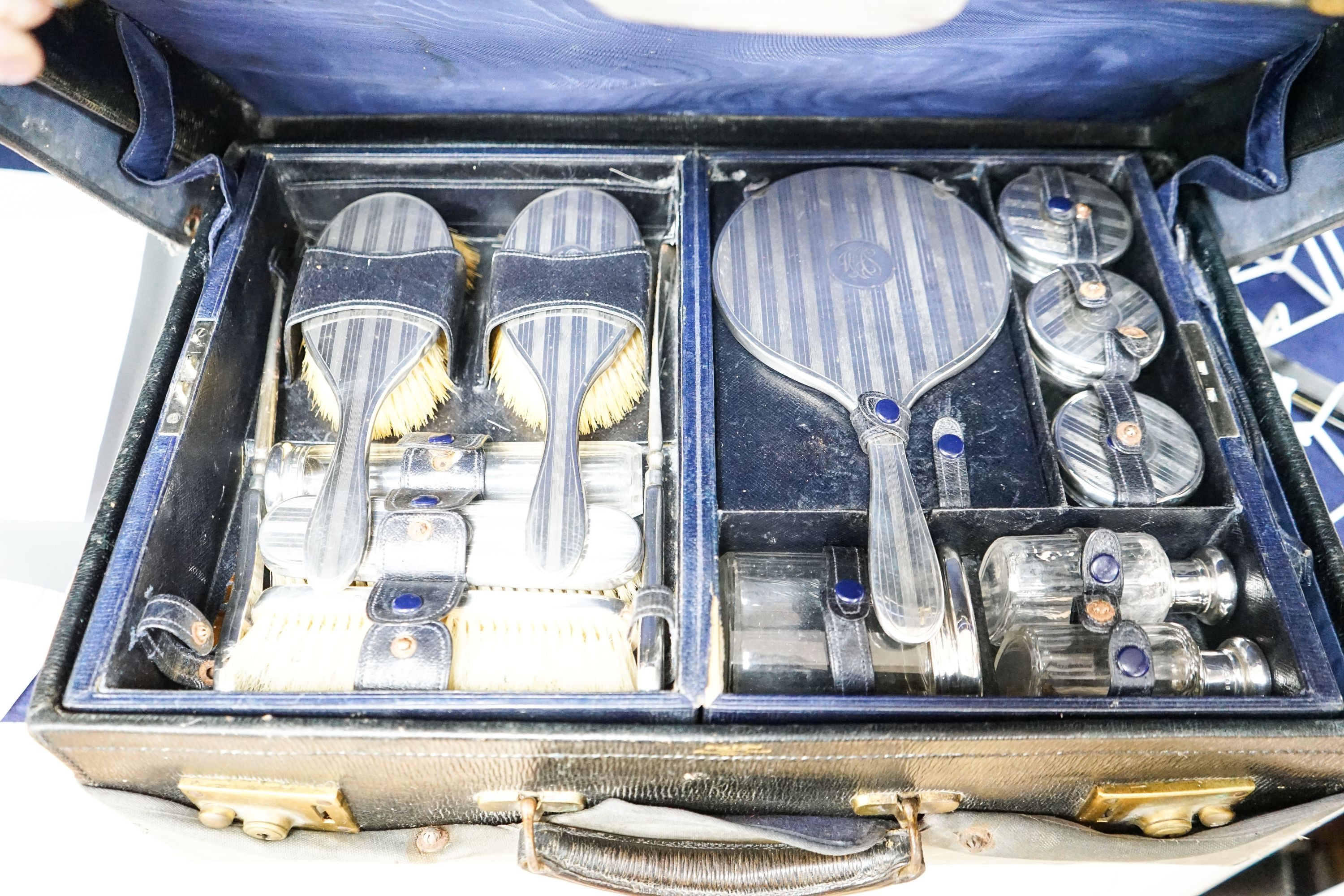 A George V traveling toilet case, fitted with fourteen silver mounted backed brushes, a mirror and toilet bottles etc. London, 19201/2.